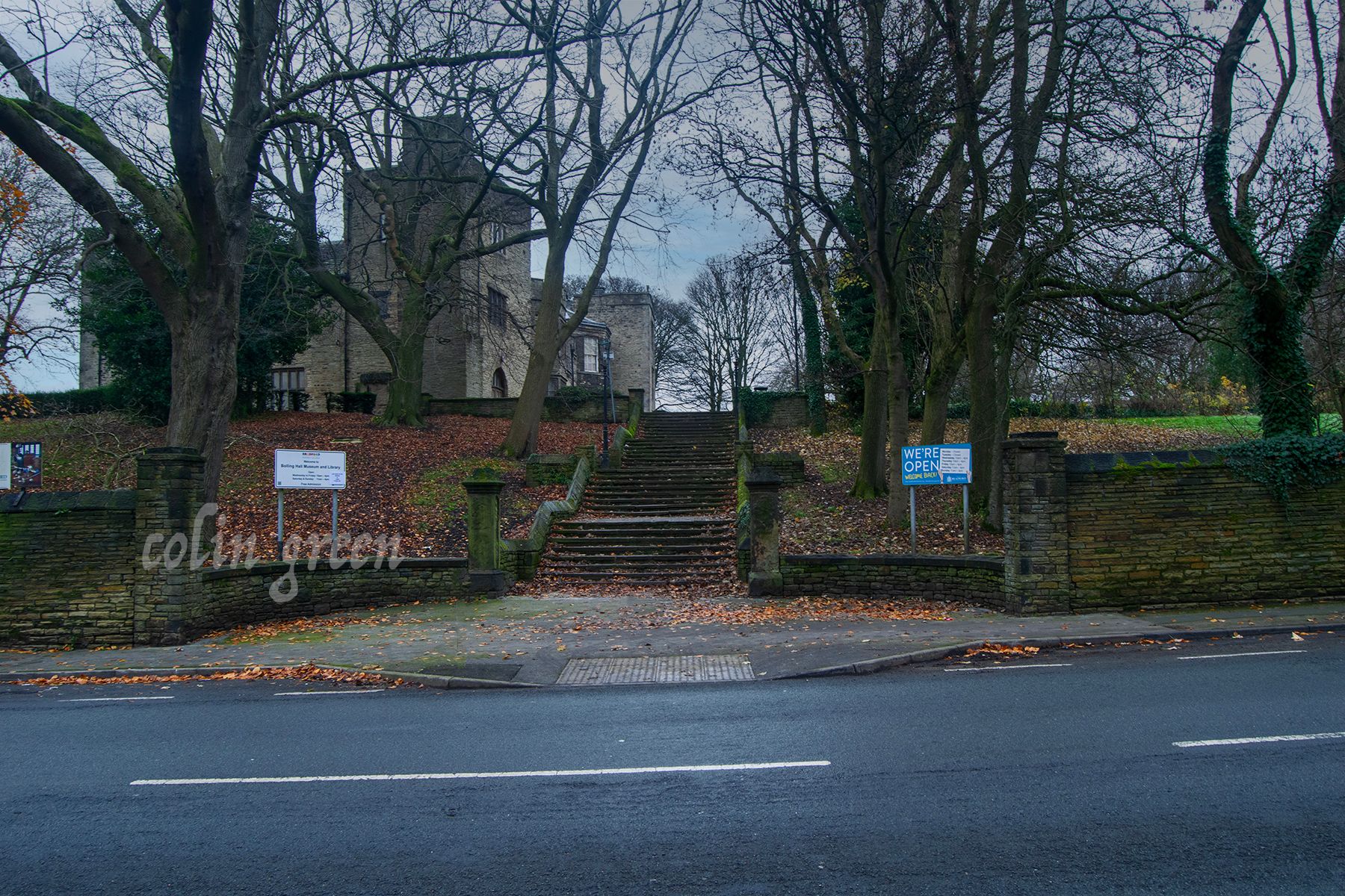 A stone staircase with uneven steps leads up to the entrance of Bolling Hall. The steps are flanked by lush green lawns and mature trees.