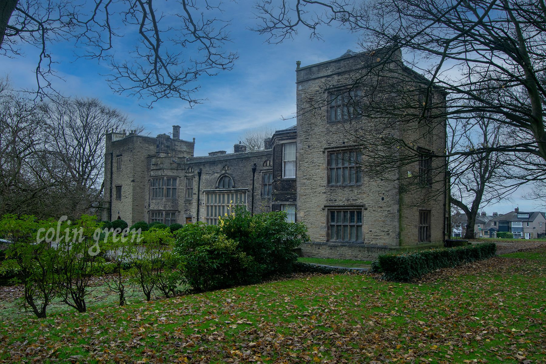 Bolling Hall, stands proudly amidst meticulously manicured lawns. Tall, mature trees provide shade and create a serene atmosphere around the historic building.