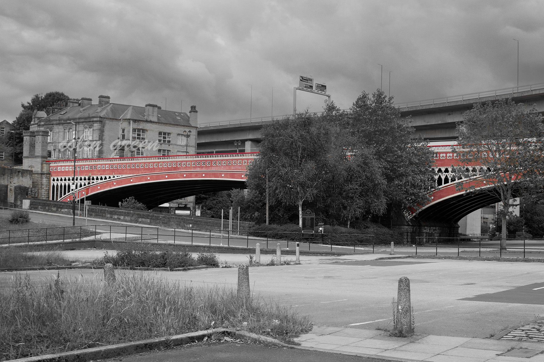 A black and white photo of the North Bridge in Halifax, England. The bridge's red brick arches stand out in contrast to the grayscale surroundings, highlighting its unique architecture