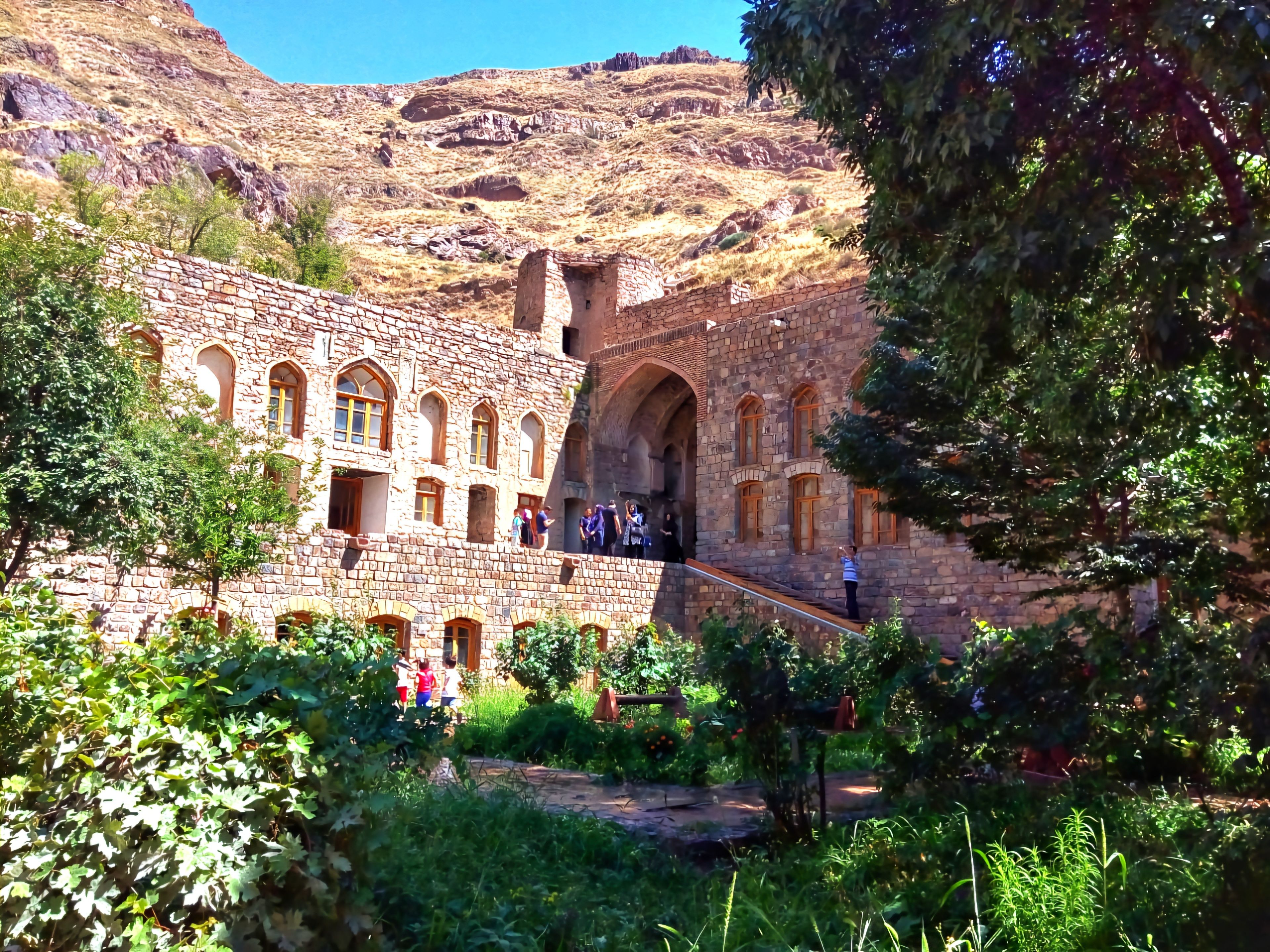 A peaceful scene of church ruins surrounded by a lush green courtyard, with majestic mountains in the background and a vast sky above, capturing the harmony between nature and history in a tranquil setting.