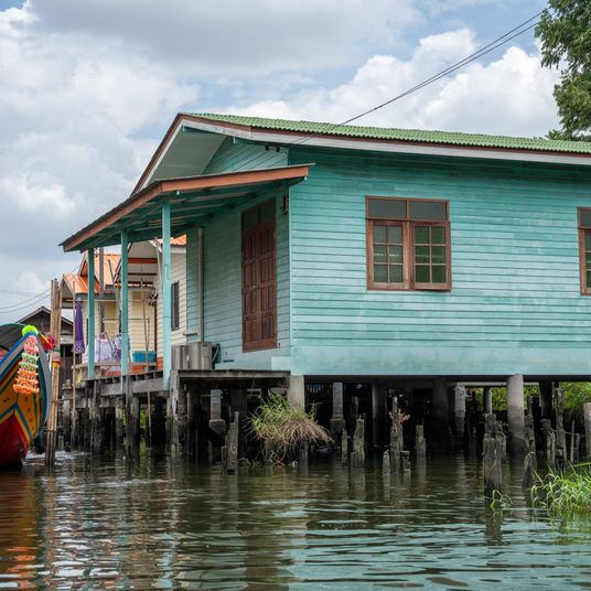 A klong or river channel of Chao Phraya river with longtail wooden boats and residential buildings in Bangkok Thailand Asia