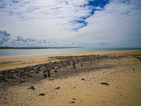 Wide expanse of sandy beach looking across river estuary towards the ocean and coastline beyond