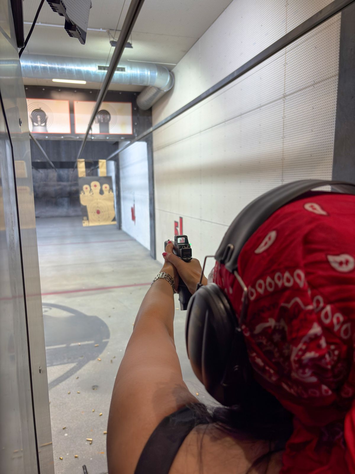 Woman aiming a handgun at paper targets in a shooting range by viton4ik ...